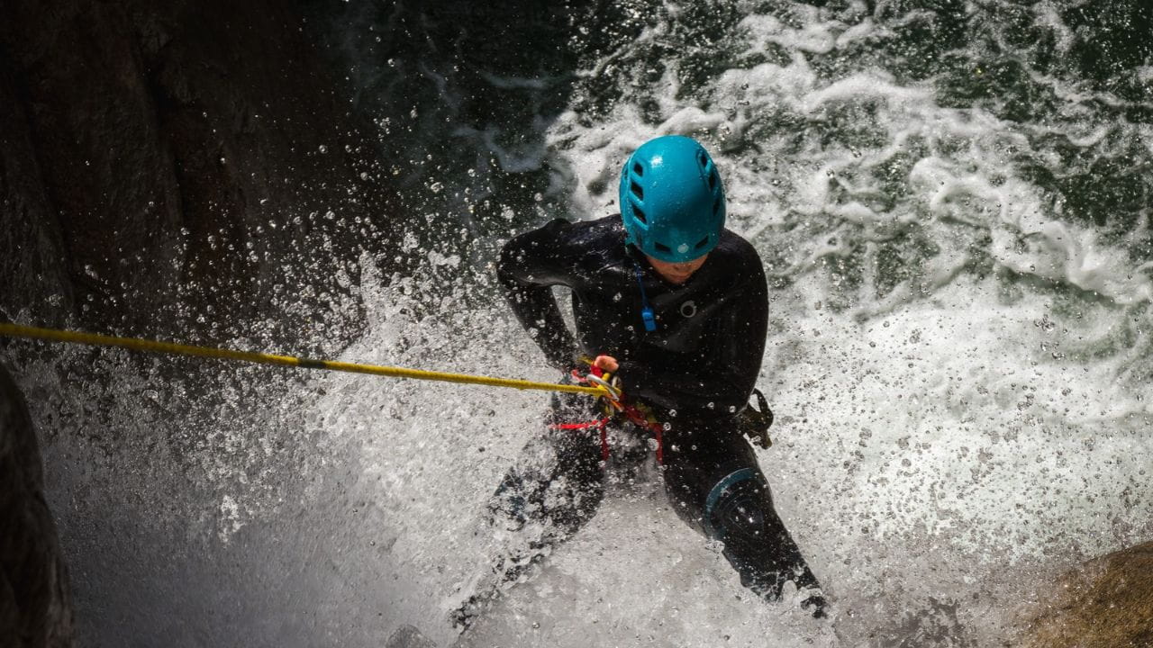 A canyoner abseiling through the spray of a powerful waterfall